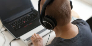 Man wearing headphones and using braille keyboard connected to a laptop